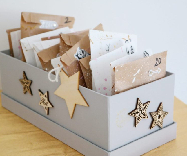 calendrier de l'avent dans une boite décorée d'étoiles avec plein d'enveloppes cadeaux dedans_atelier calendrier de l'avent_l'atelier en ville_nivelles