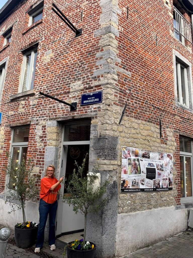 Cécile devant l’entrée de L’Atelier en Ville, atelier créatif à Nivelles proposant des activités créatives accessibles depuis le Brabant wallon, le Hainaut et Bruxelles