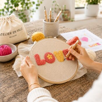 Mains créant le mot LOVE au punch needle — atelier créatif Nivelles